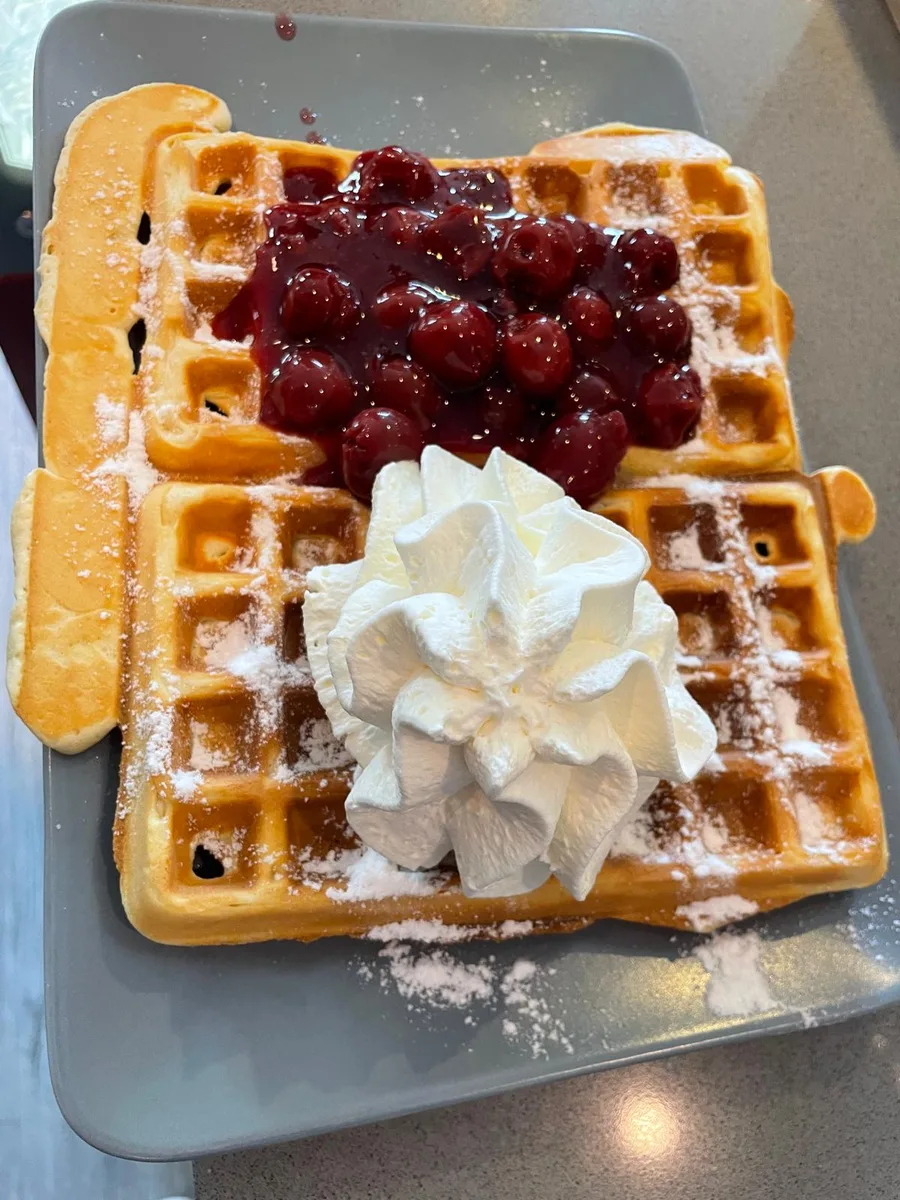 Fresh waffle with cherries and whipped cream